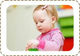 A baby girl playing with toys in her room.