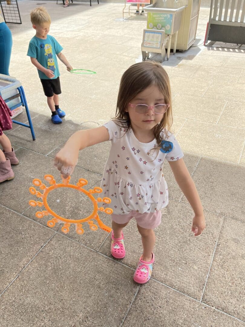 A little girl holding an orange sun shaped object.