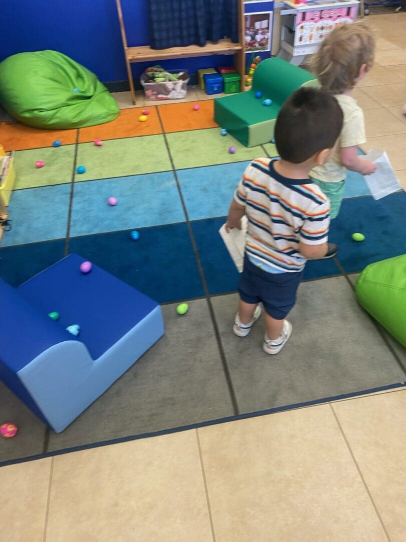 A boy standing on the floor of an indoor play area.