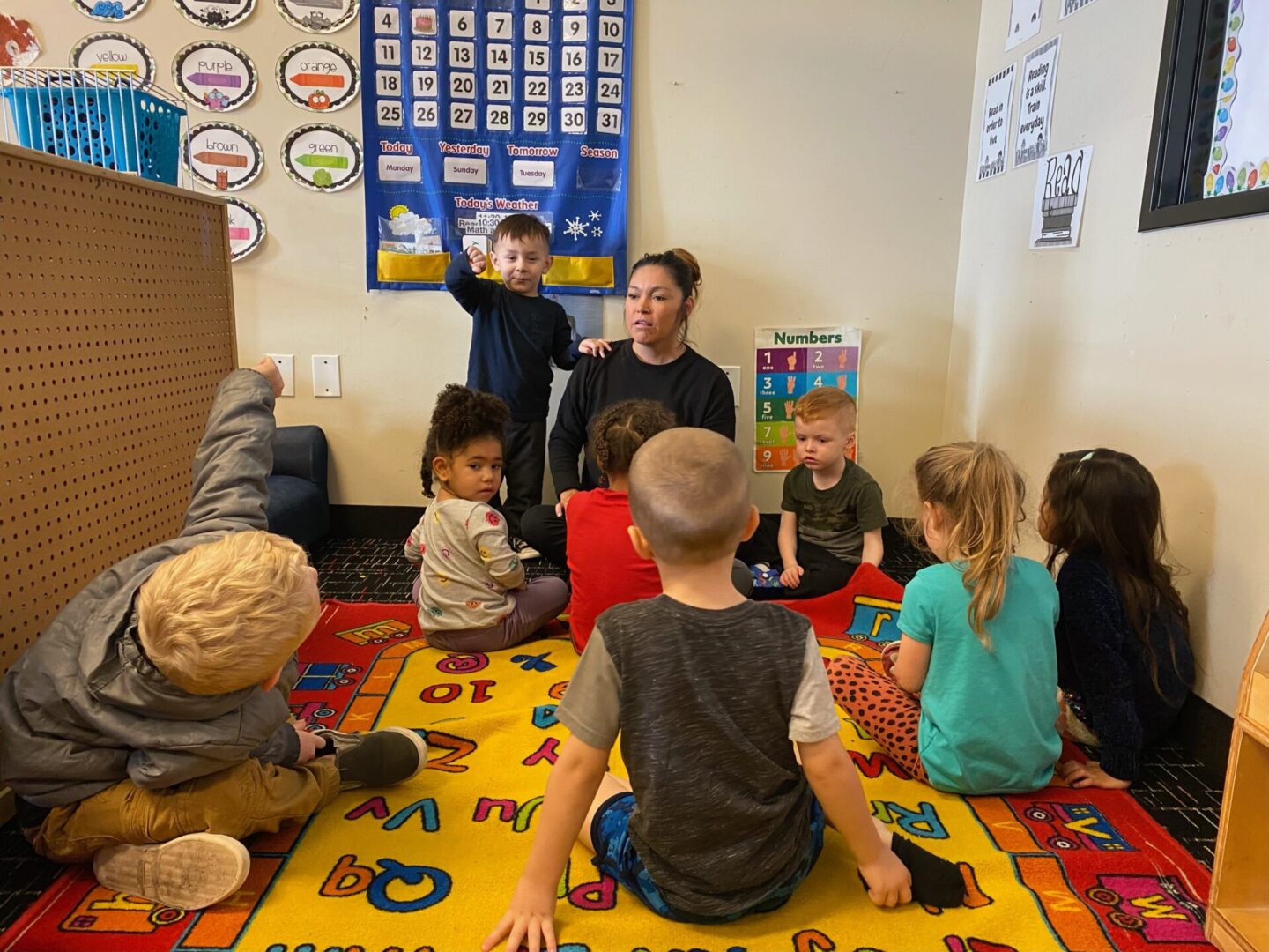 A group of children sitting on the floor in front of an adult.