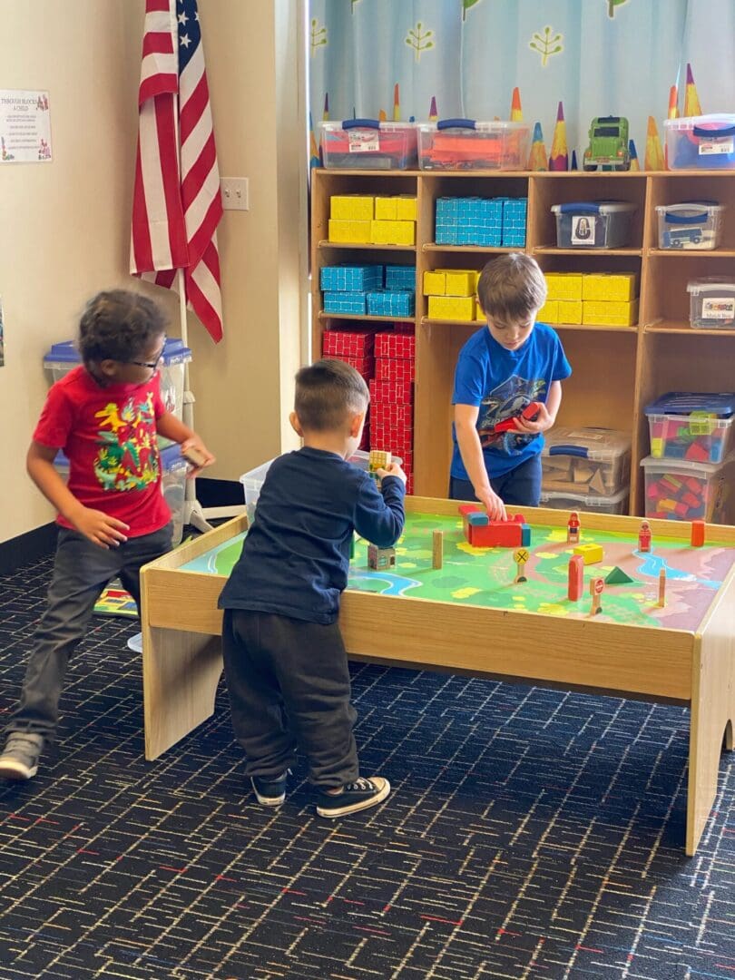 Three children playing with a table in the room.