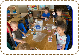 A group of children sitting at a table playing with cards.